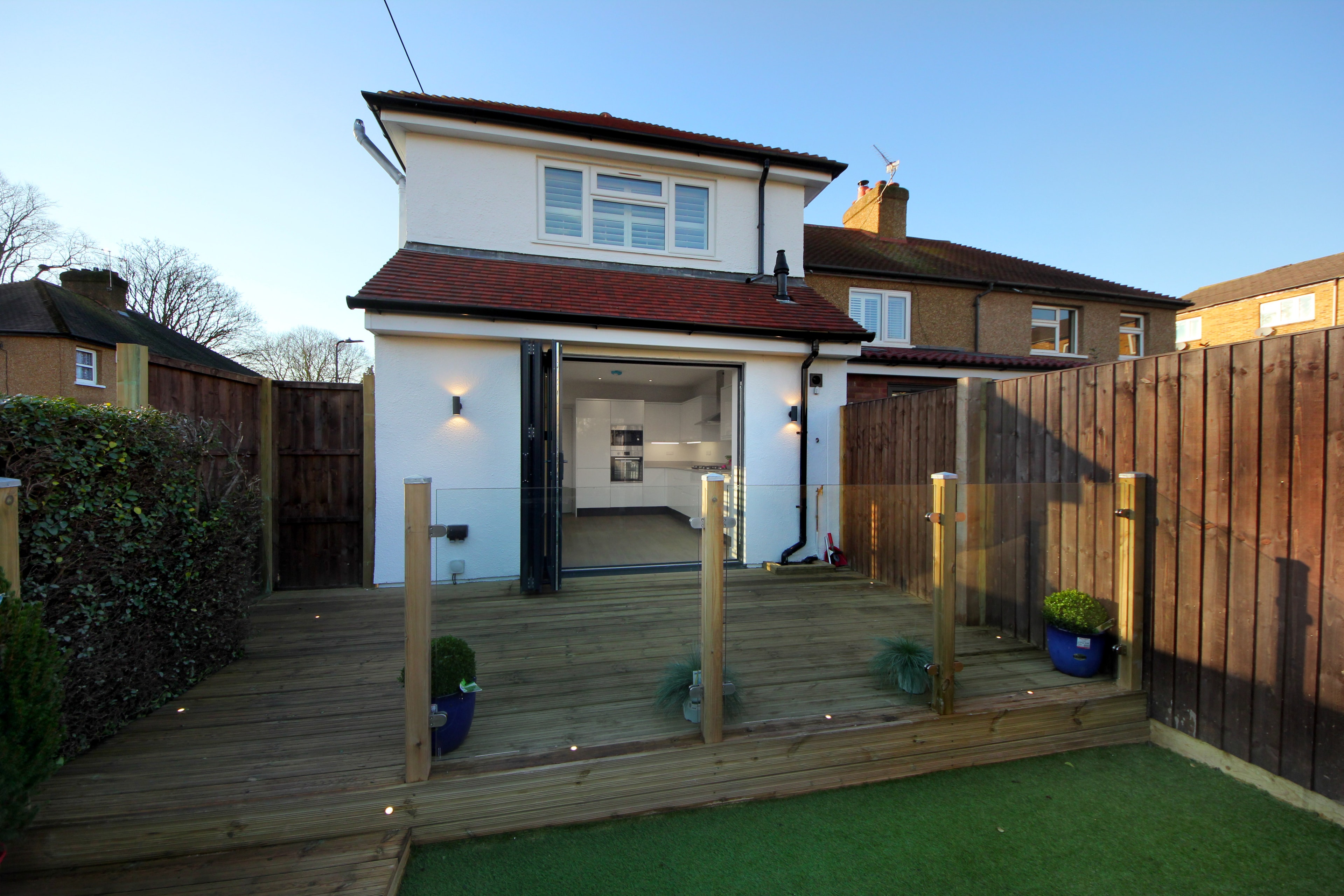 Chilton Avenue — rear extension with bifold doors open to new timber decking and landscaped garden at dusk