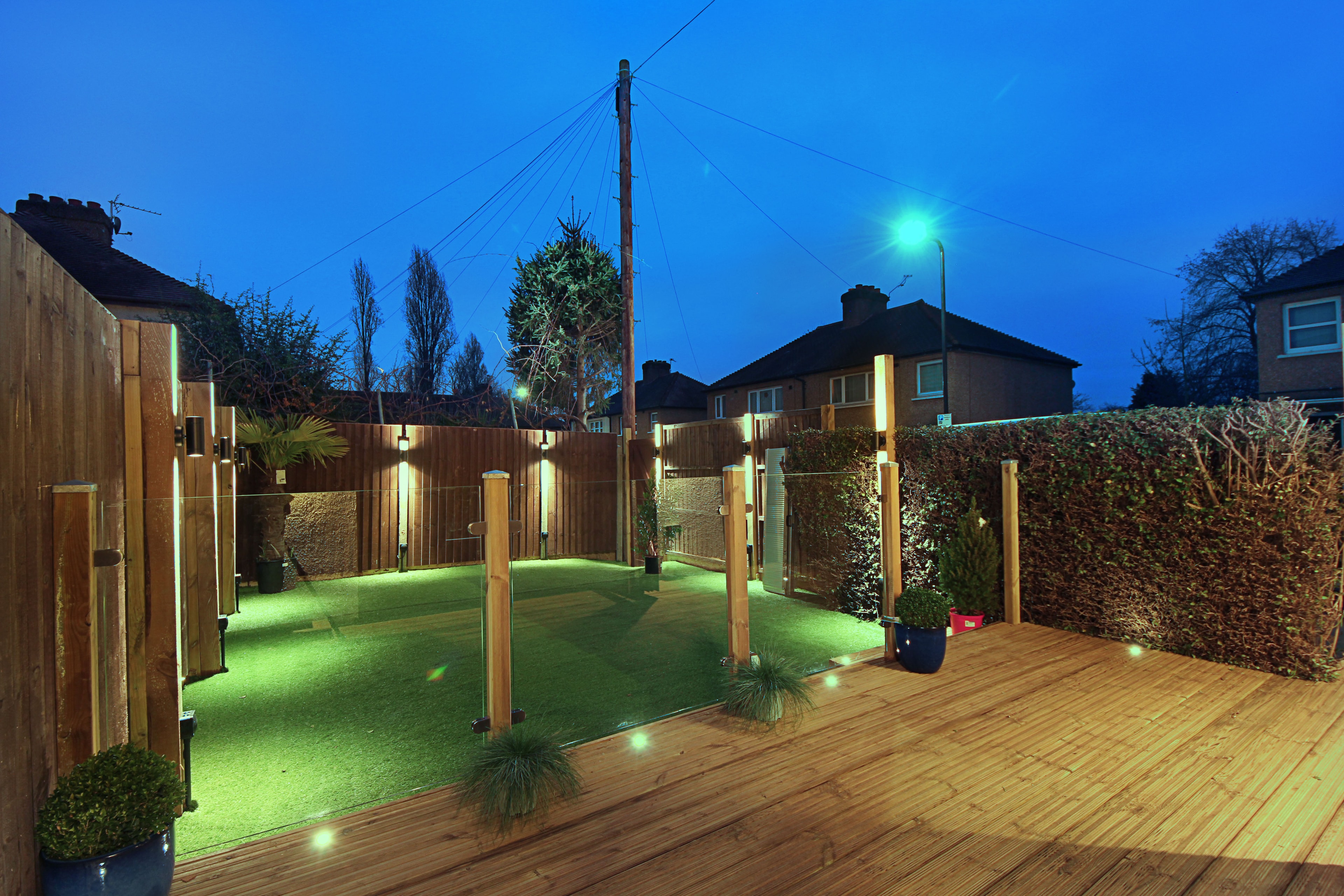Chilton Avenue — kitchen interior at dusk with bifold doors open to illuminated garden and decking