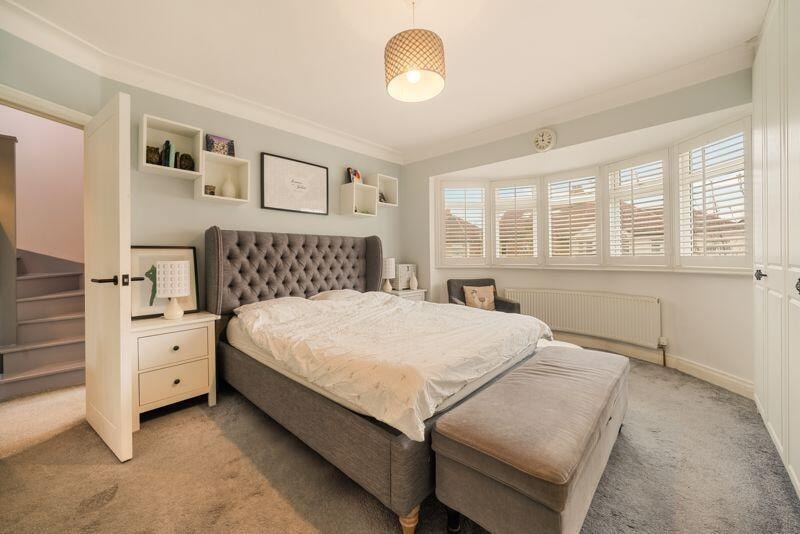 Master bedroom with upholstered headboard and plantation shutters