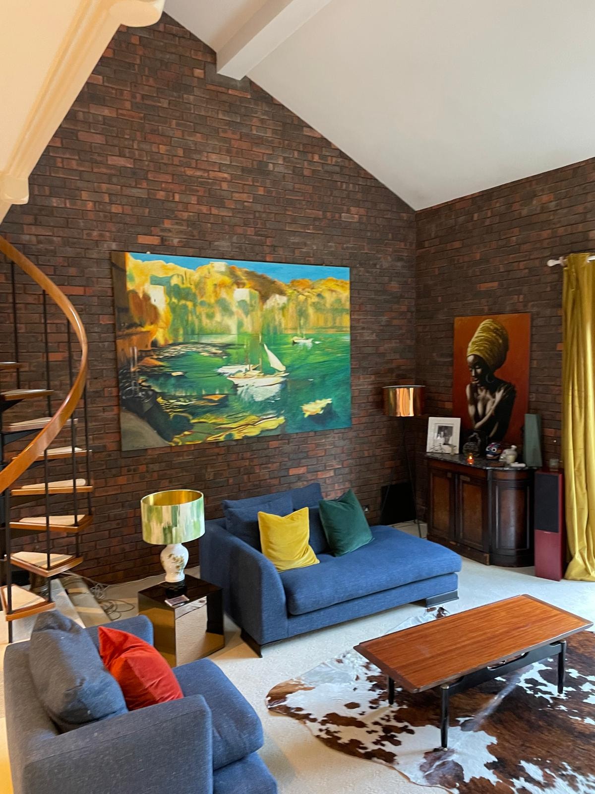 Galley Lane — existing sitting room with exposed brick walls, blue sofas, large artwork and spiral staircase before works