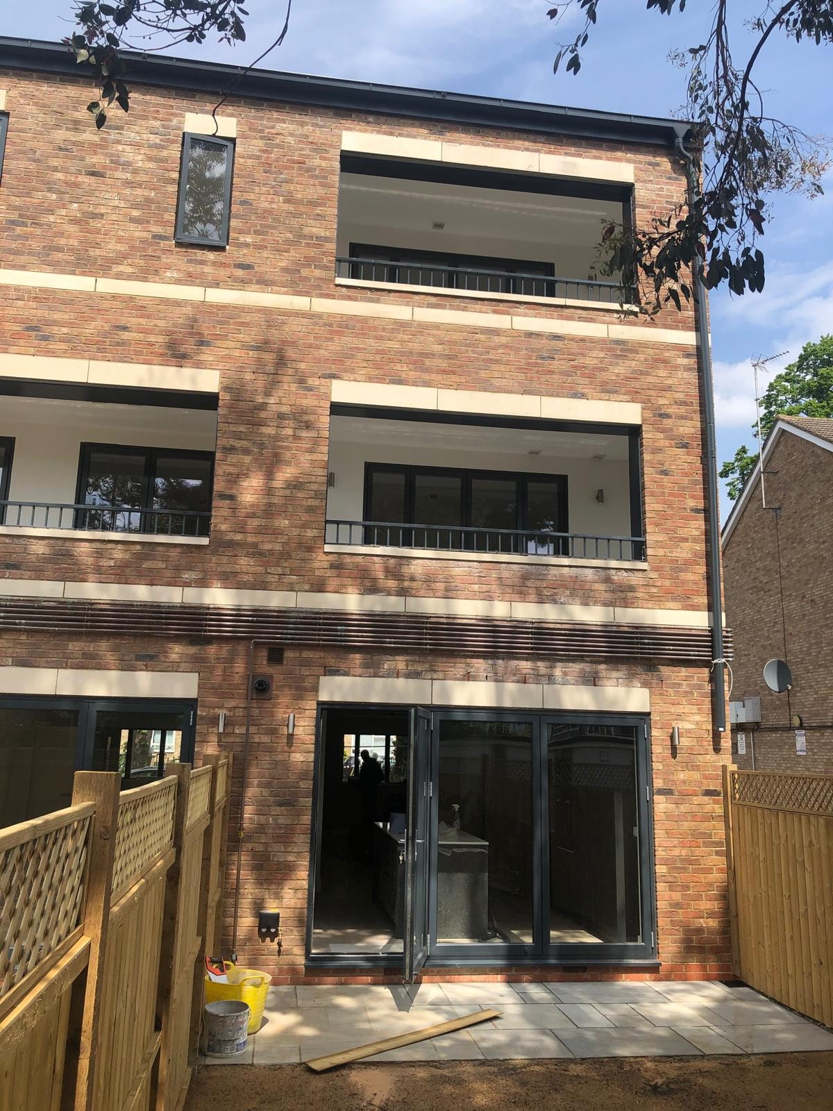 Golden Manor — completed rear elevation showing bi-fold doors opening to private patio and garden