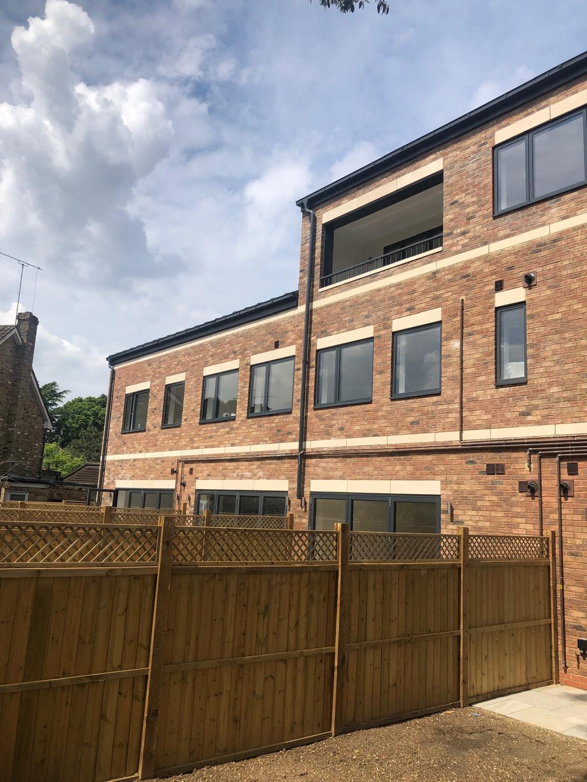 Golden Manor — completed rear elevation showing brick and stone banding with dark aluminium windows