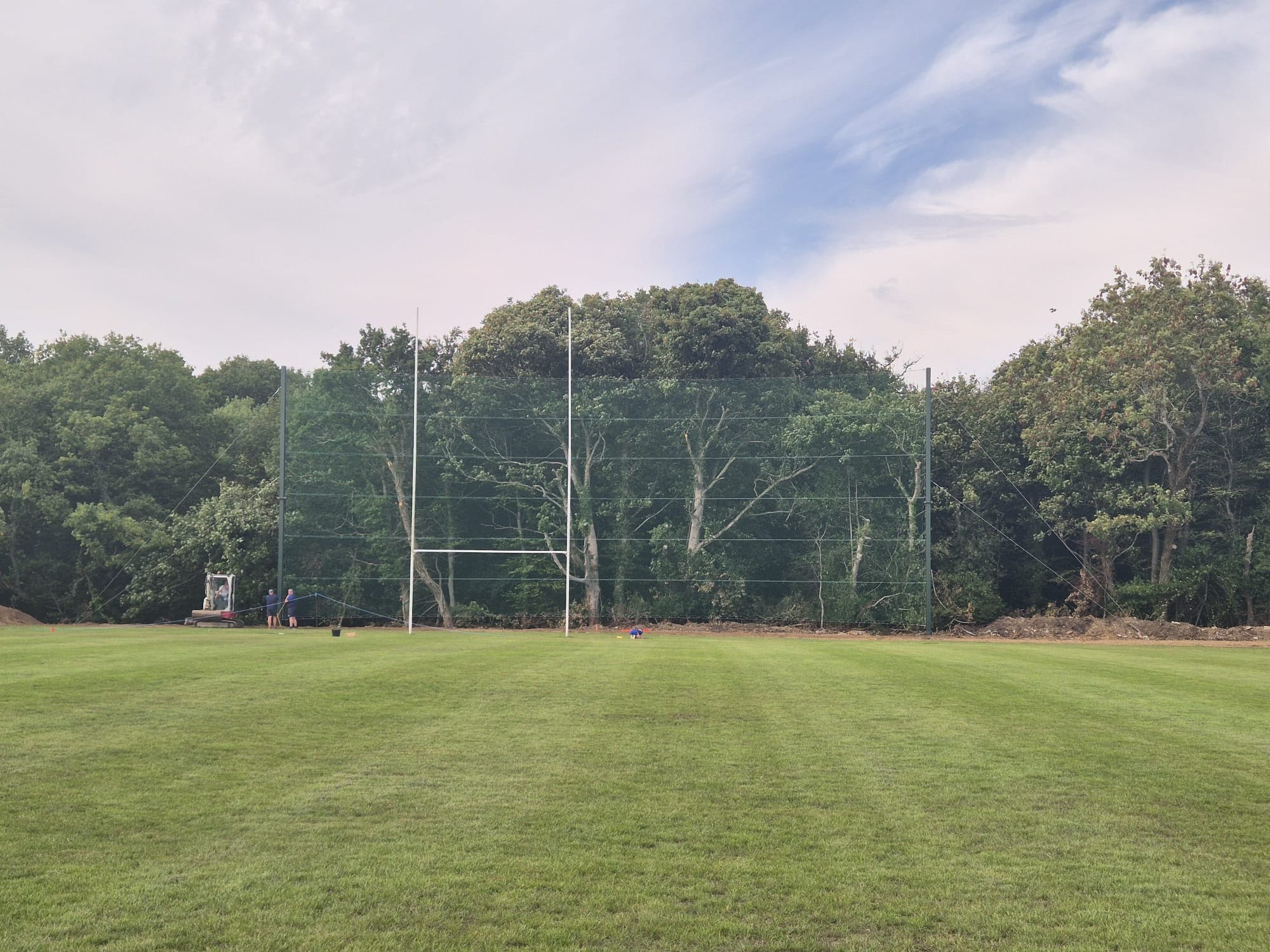 Rugby posts and net viewed from pitch with workers on site