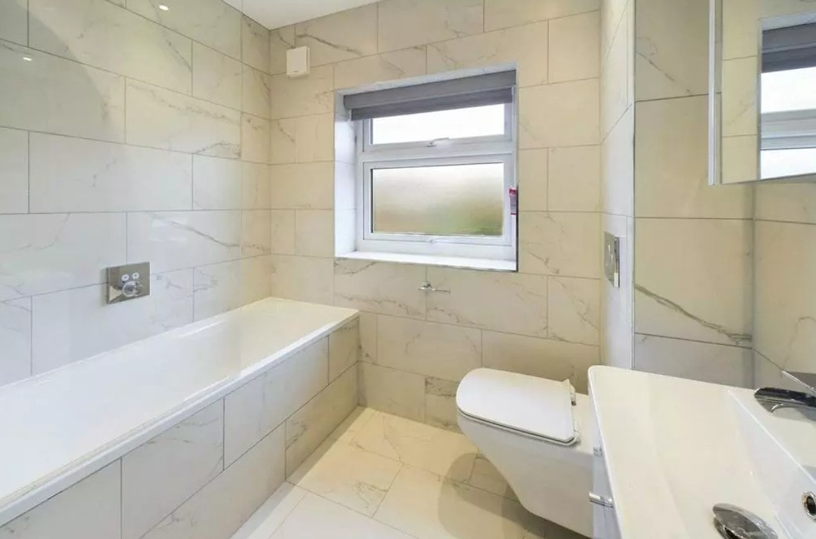 Hillside — completed bathroom with marble tiles, bath and wall-hung WC