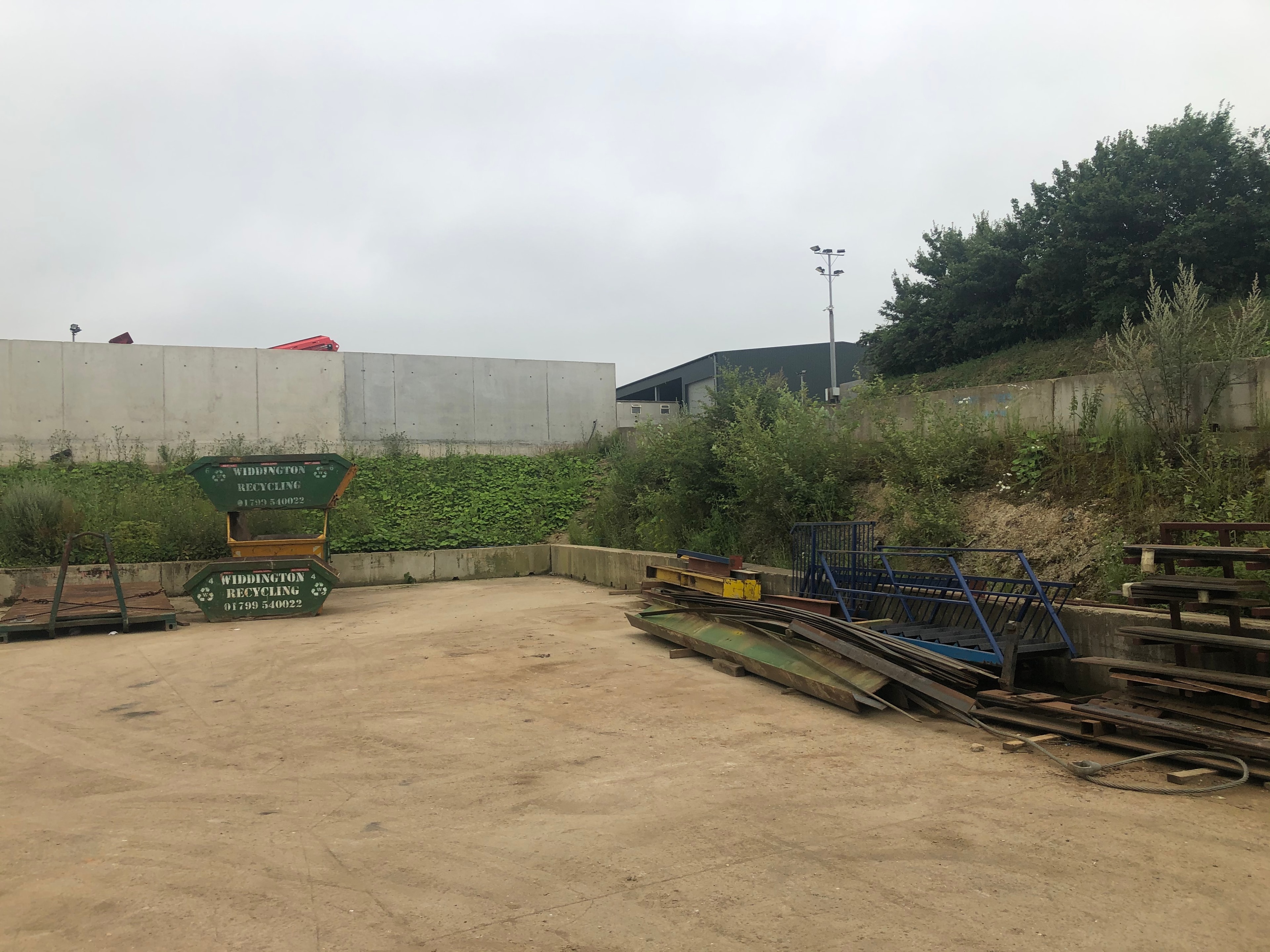 Widdington Recycling — existing site with concrete retaining walls and skip storage area