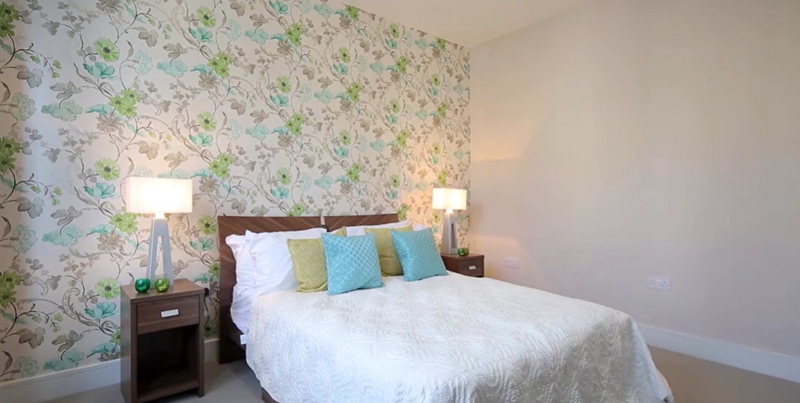 Bedroom with green floral wallpaper and coordinated soft furnishings