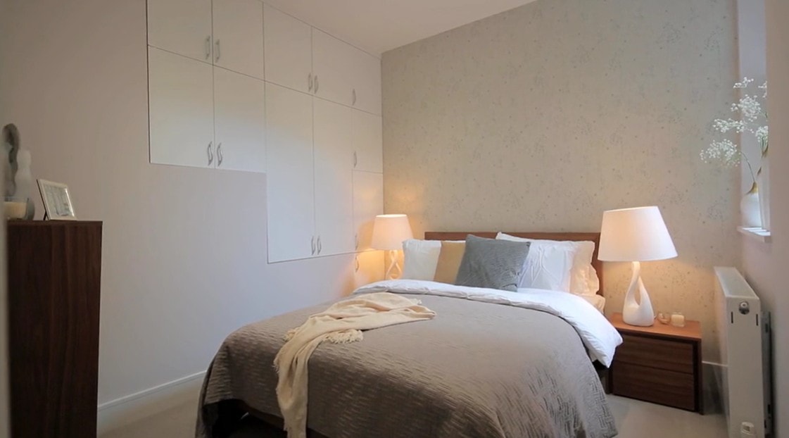 Second bedroom with neutral wallpaper and fitted wardrobes